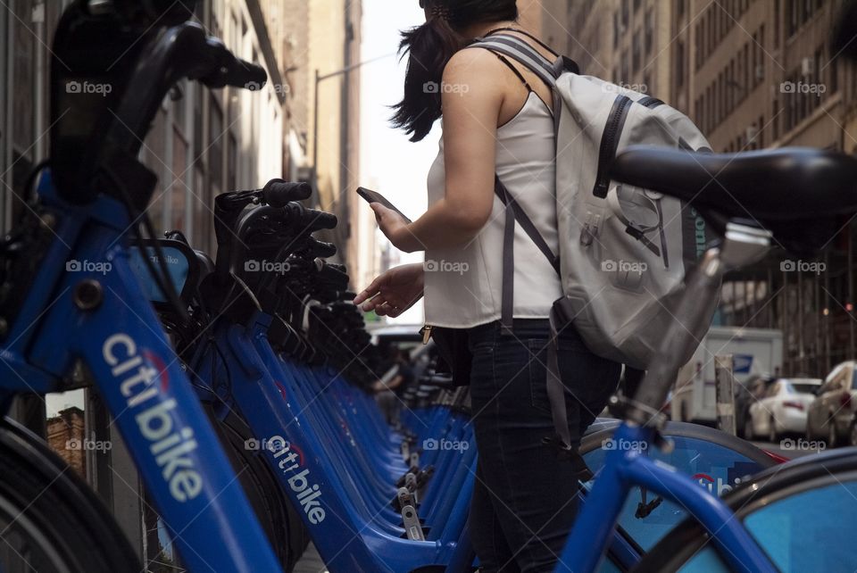 A young woman takes out her cell phone to pay for a citibike in New York city.