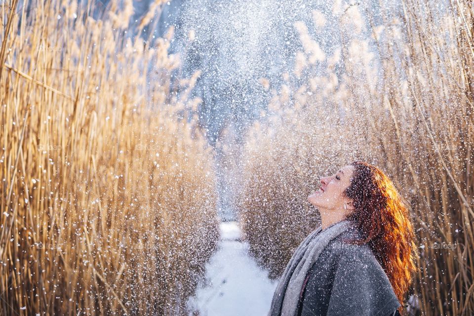 Snow falling on a young woman in forrest of reeds