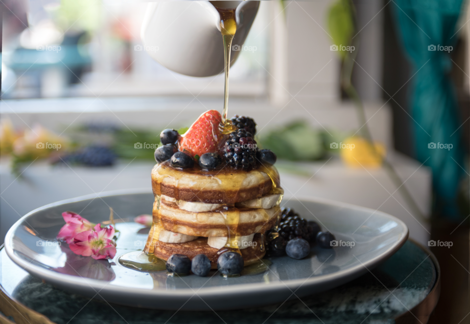 A stack of pancakes with syrup being poured 