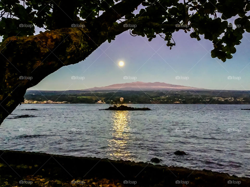 Moon receding as the sun illuminates the volcano