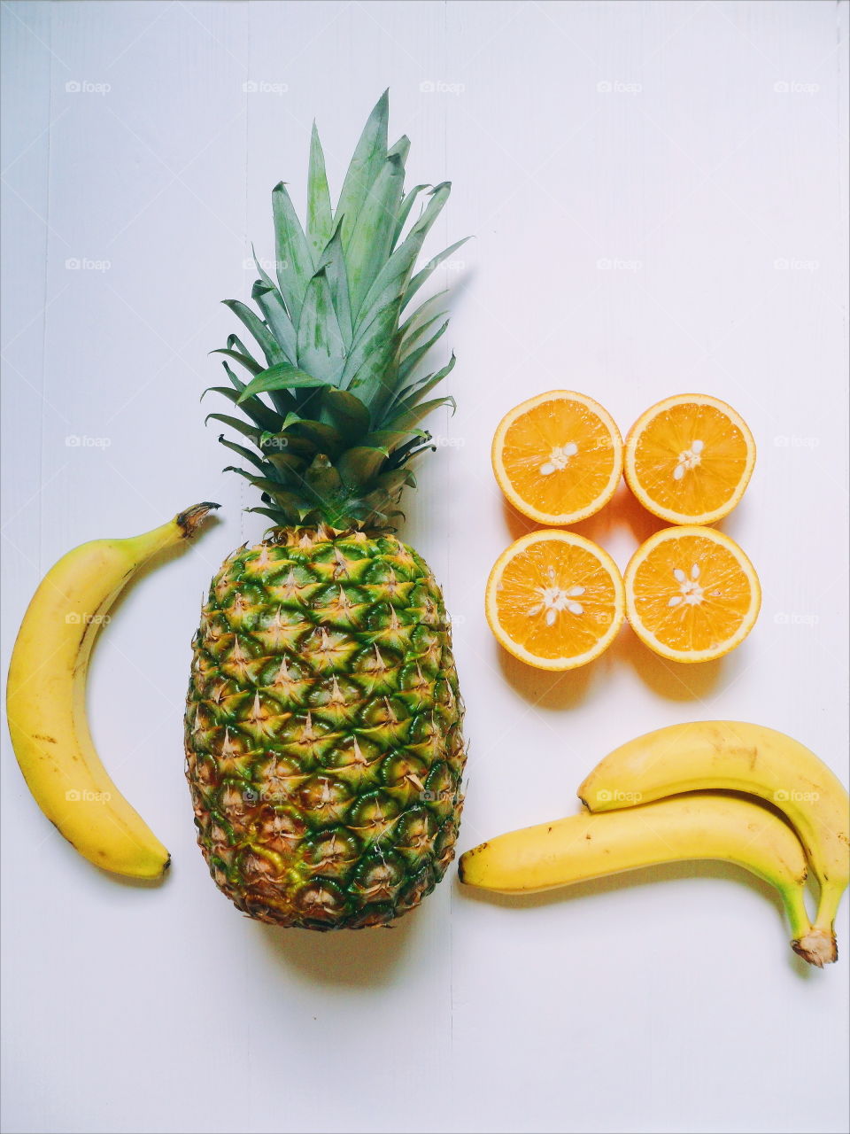 pineapple, sliced ​​orange and bananas on a white background