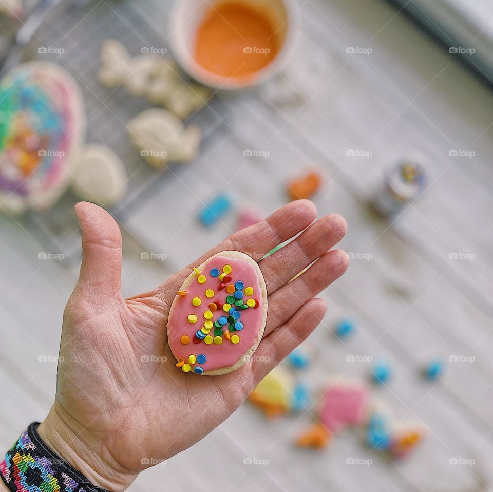 Woman’s hand holding colorful cookie, making cookies with toddlers, colors of spring, making Easter cookies with kids, colors of Spring in cookies 