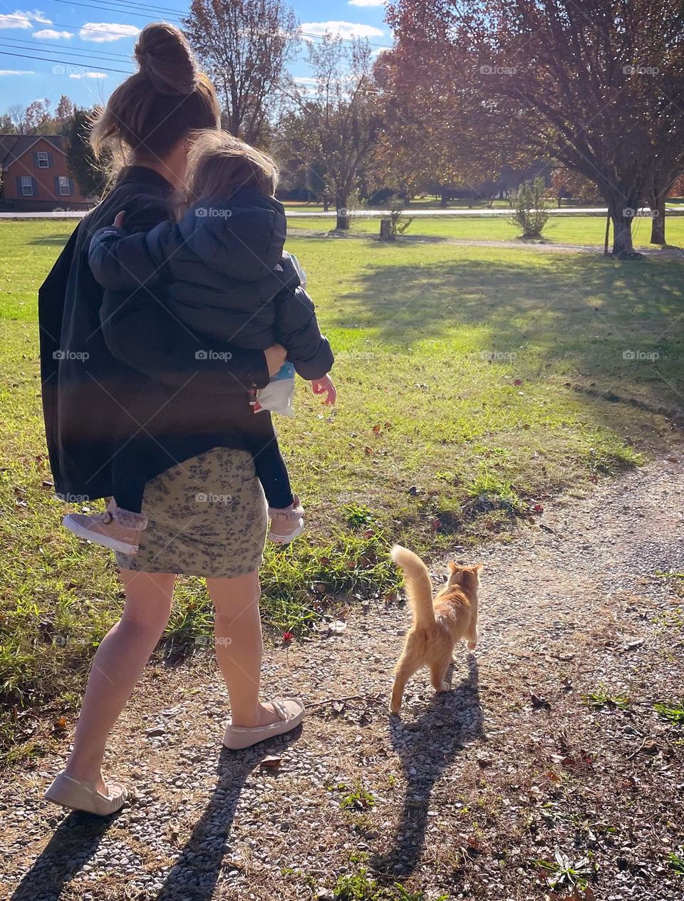 A mother carries her young child along a rural road as the family cat stays close by in Mount Juliet, Tennessee 