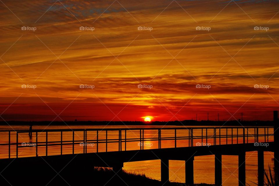 Silhouette bridge over sea against sky