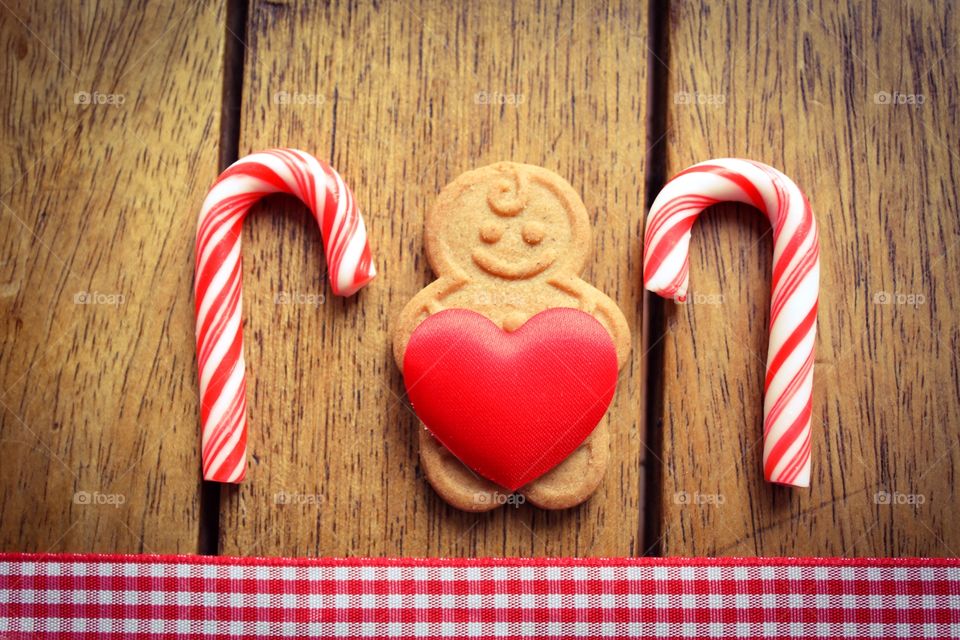 Gingerbread man holding a red love heart with candy cane 