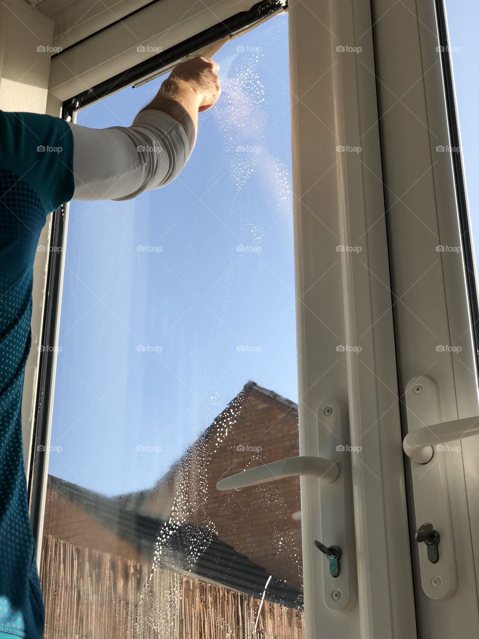 A lady cleaning her patio door window 