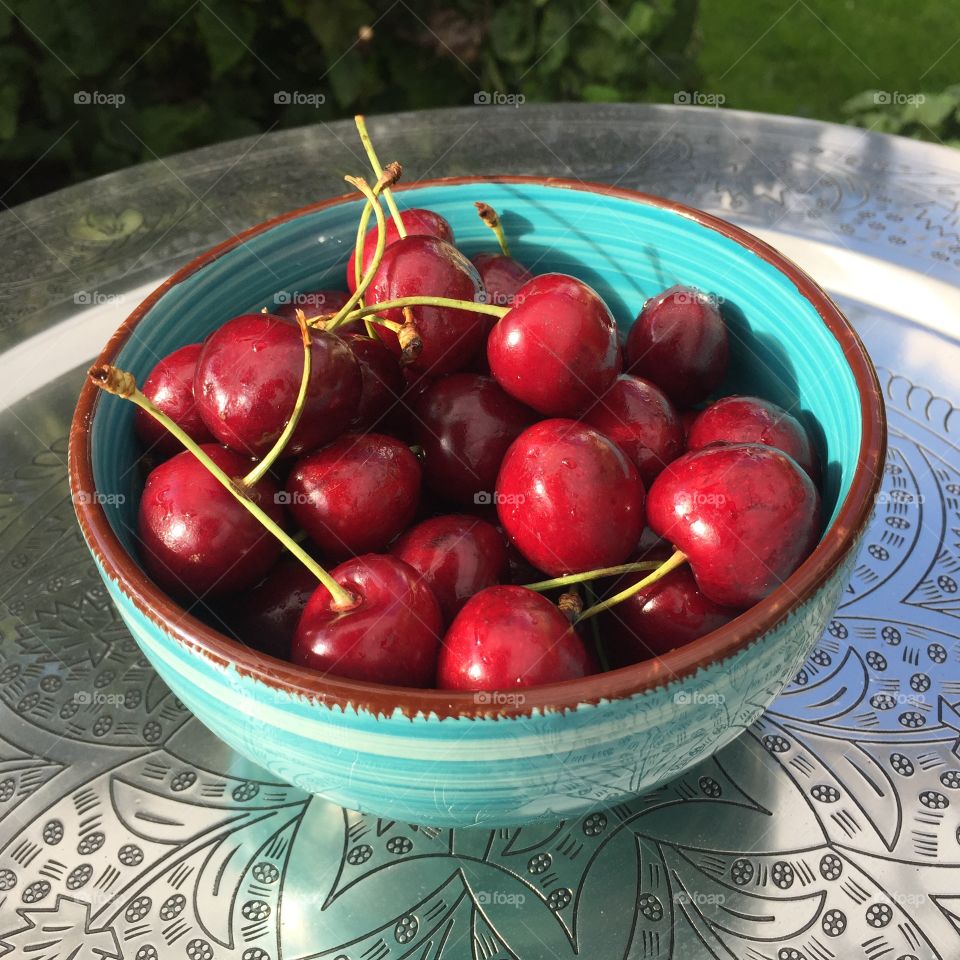 Cherries in a turquoise bowl on silver plate