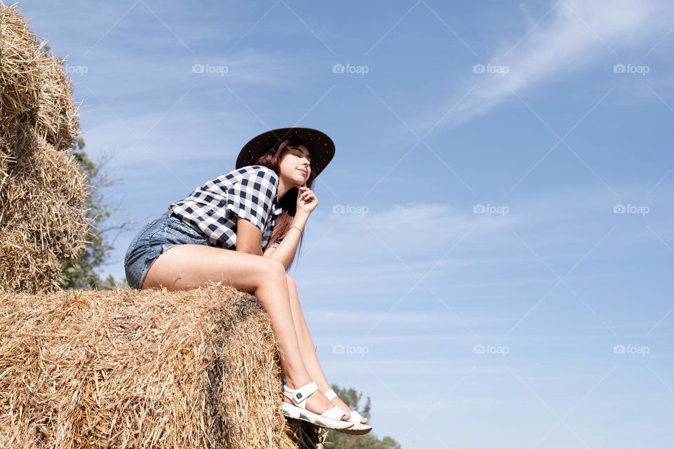 woman in cowboy hat sitting on hay stack