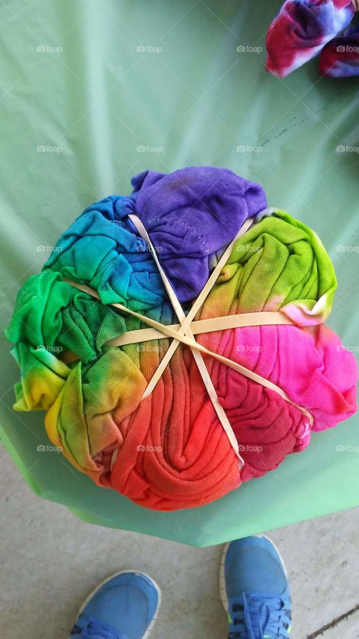 Colorful tye dye t-shirt rolled up and secured with rubber bands