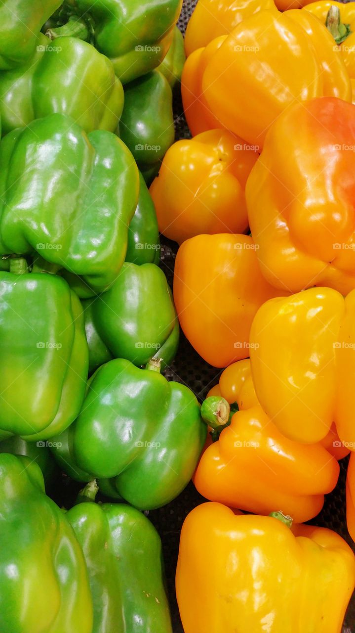 Green and yellow capsicums (bell peppers) on display in a local market.