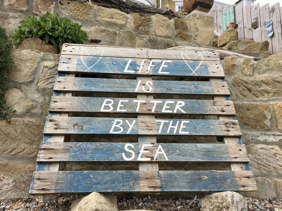 Life is better by the sea ... words written on an old pallet in a garden by the beach 