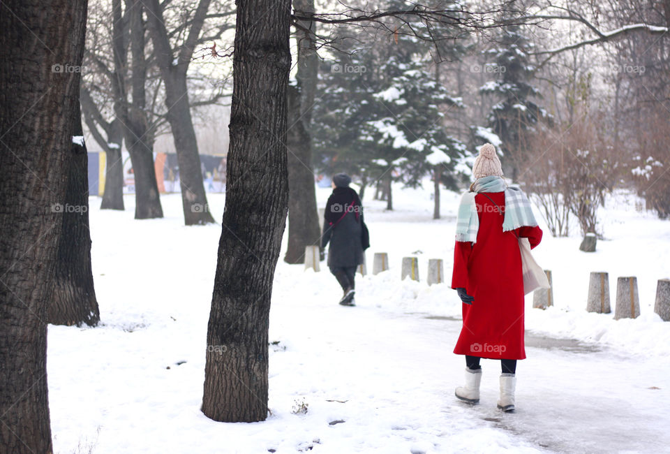 A woman in red coat in the winter park