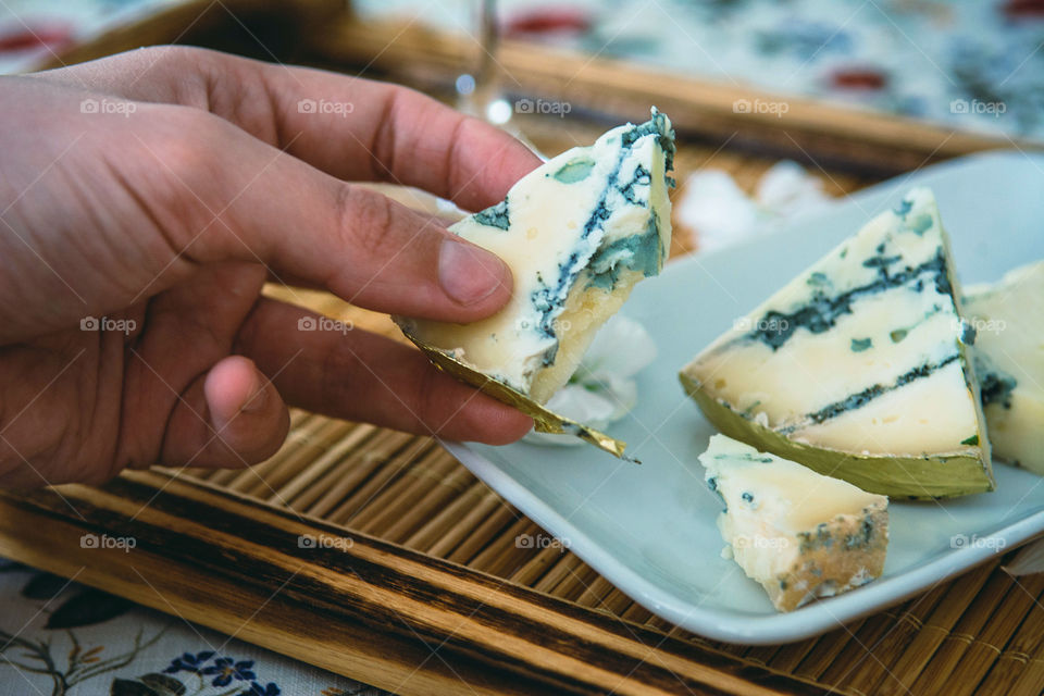 Human finger holding cheese