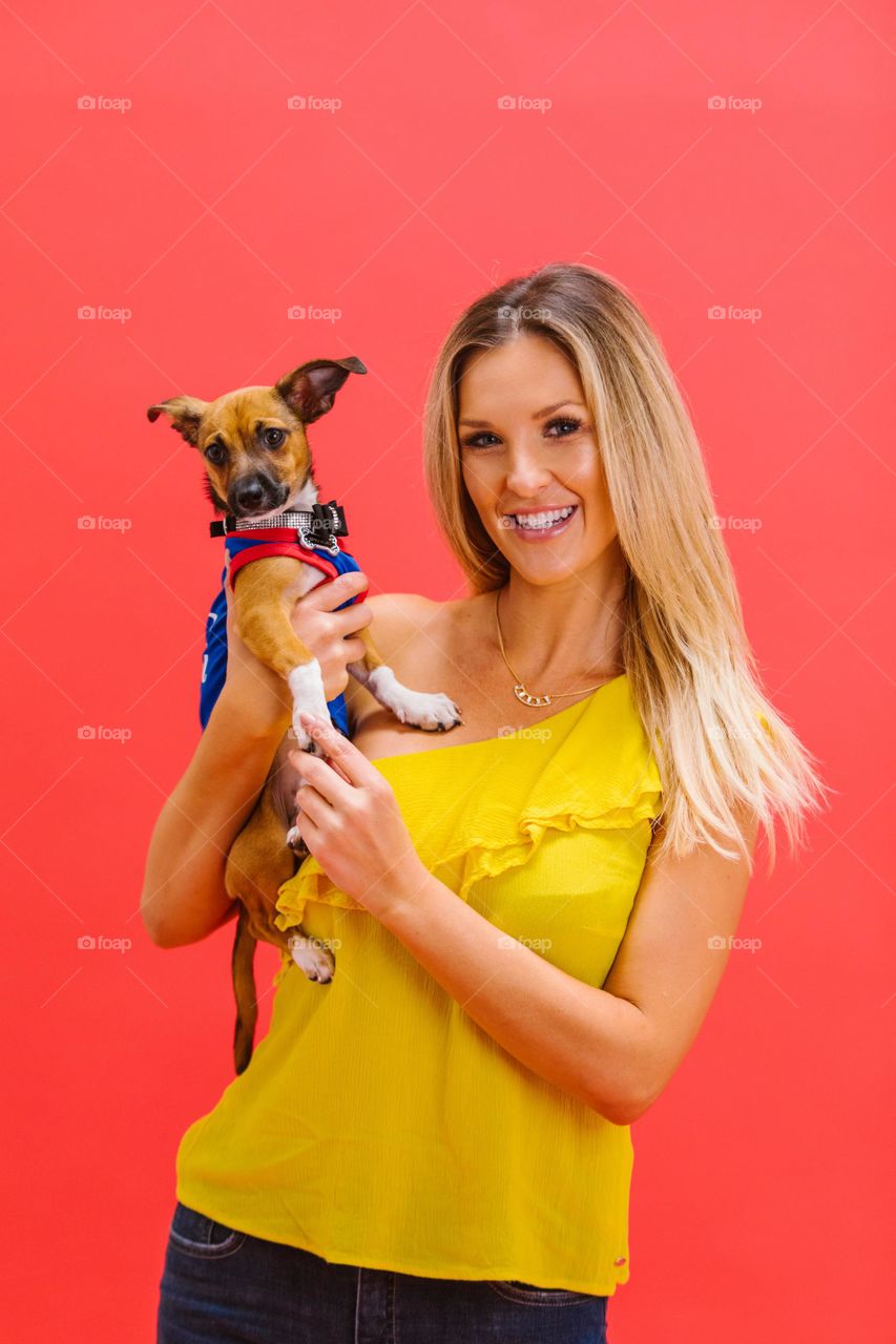 cachorro no colo da dona vestida de amarelo com fundo vermelho