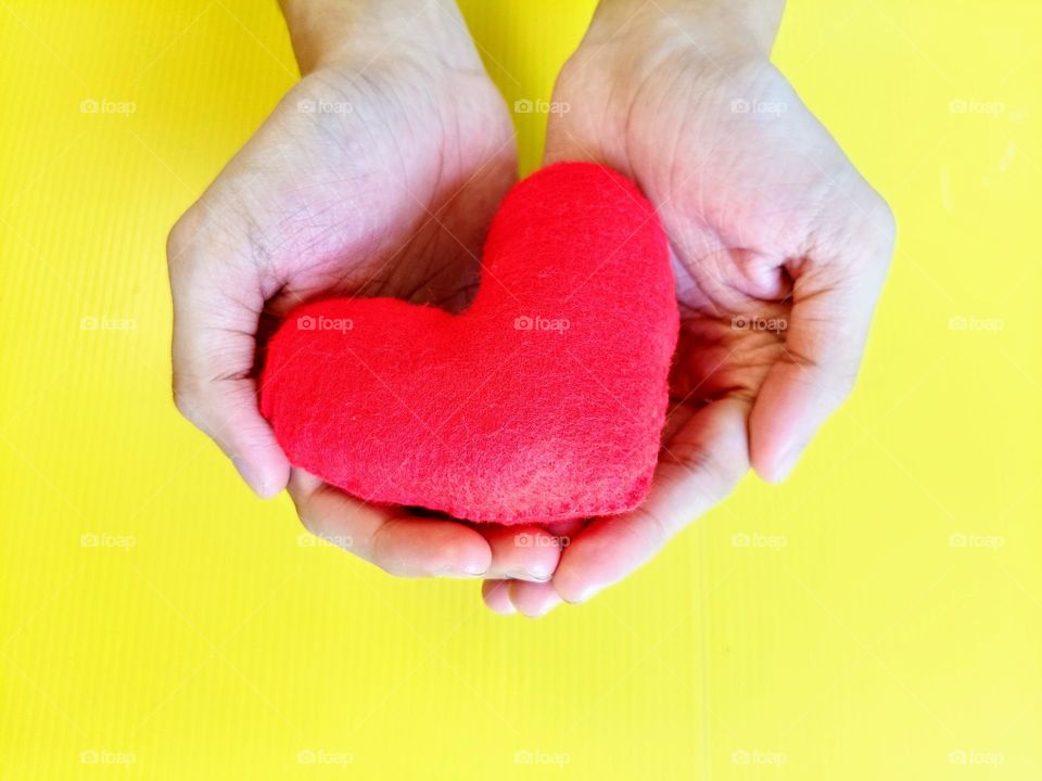 Giving heart on yellow background horizontal composition.