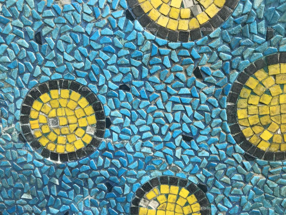 yellow and black pieces of square tile created as amazing circle pattern and blue color as ocean surface