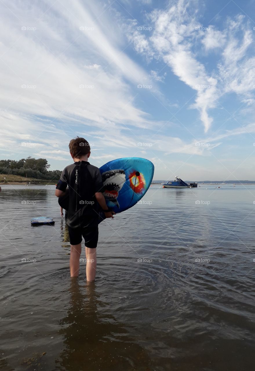 Boy with boogie surfboard at seaside