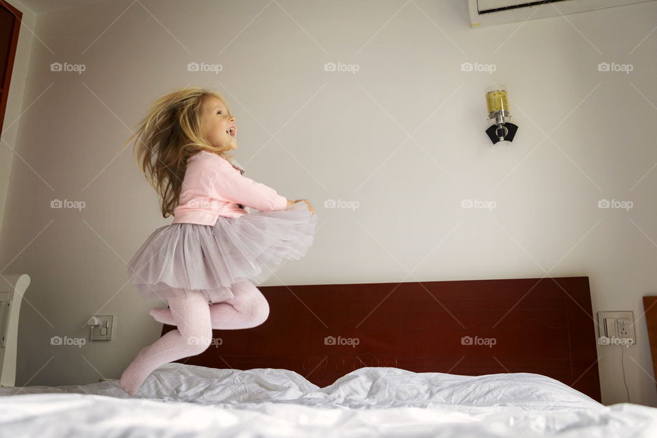 Cute little girl jumping on the bed 