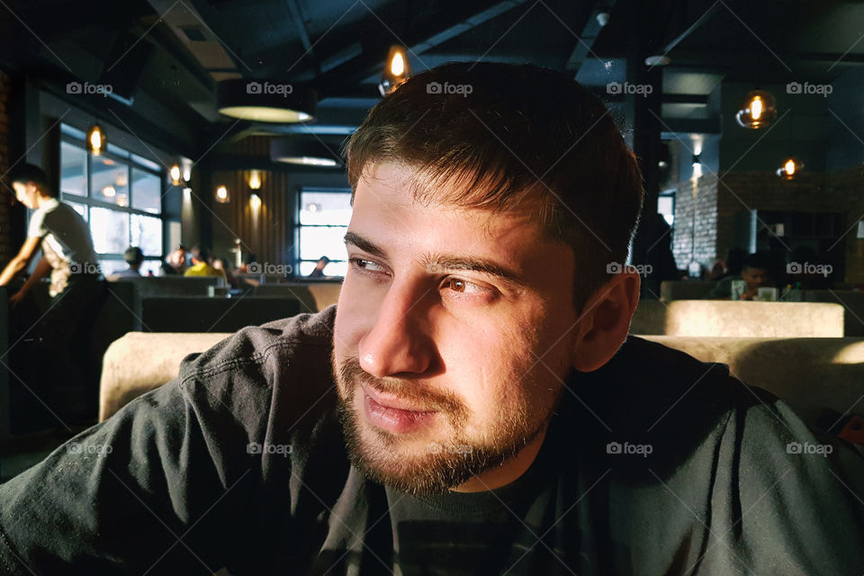 young man is dreaming in a modern urban cafe . close up