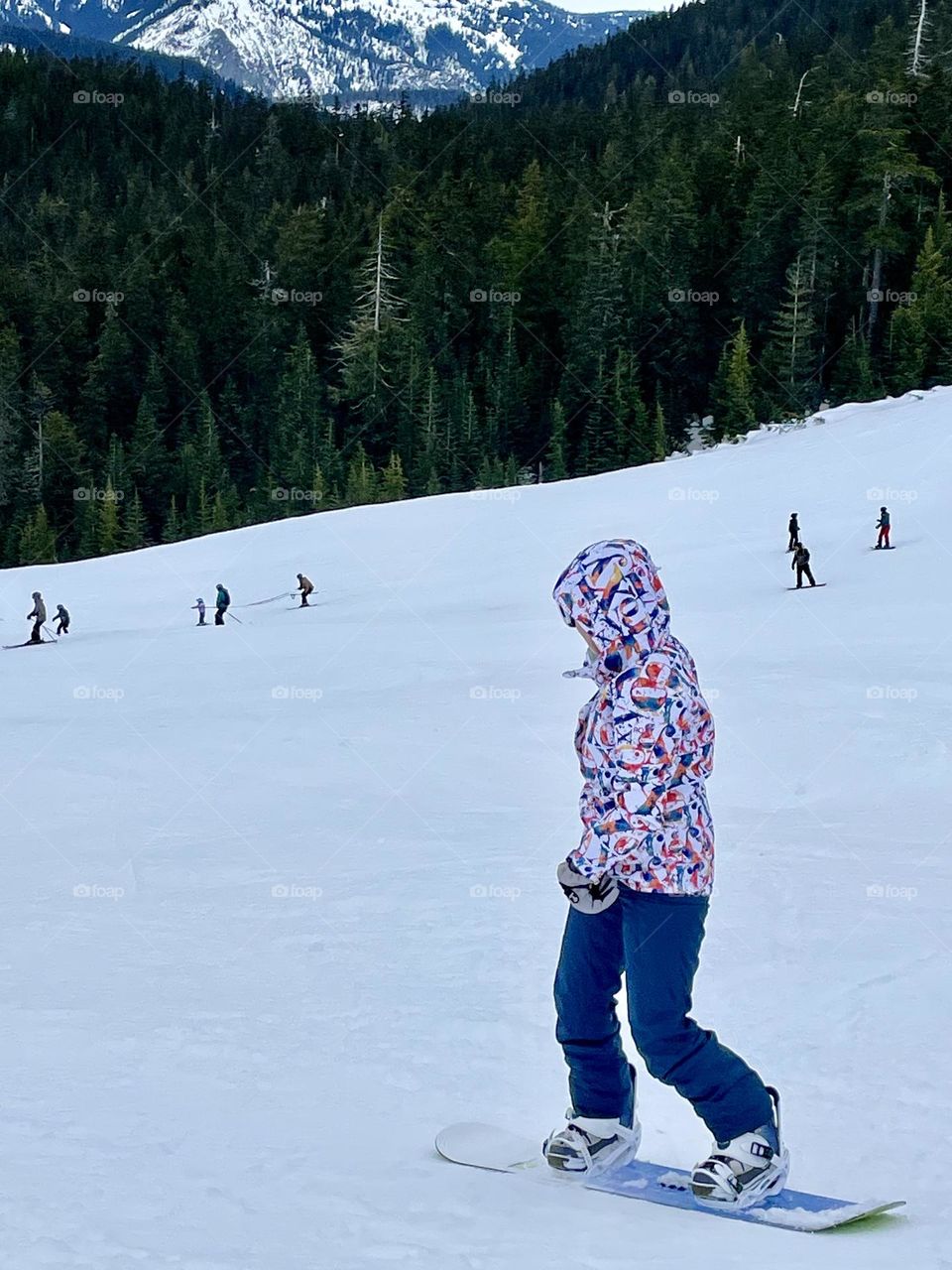 A female snowboarder traverses down the ski slope on a clear day at White Pass Ski Resort in Washington State. 