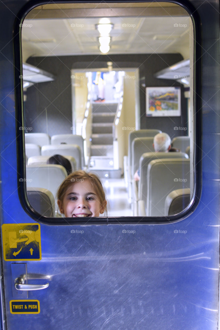 Portrait of a smiling girl looking through door