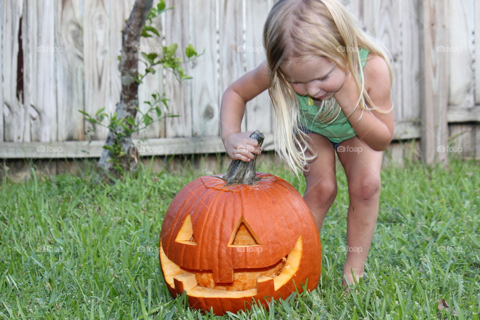 Young girl holding pumpkin stem in yard