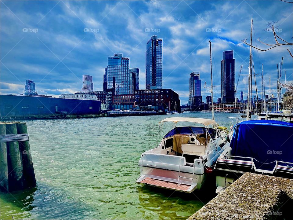 On a brightly but unusually colored early afternoon in January 2023 by the waterfront of the “East River” at “Newtown Creek” by the “Pulaski Bridge” the multiple cumulus clouds in the sky are mirrored back by the waters below. Hypnotic Productions
