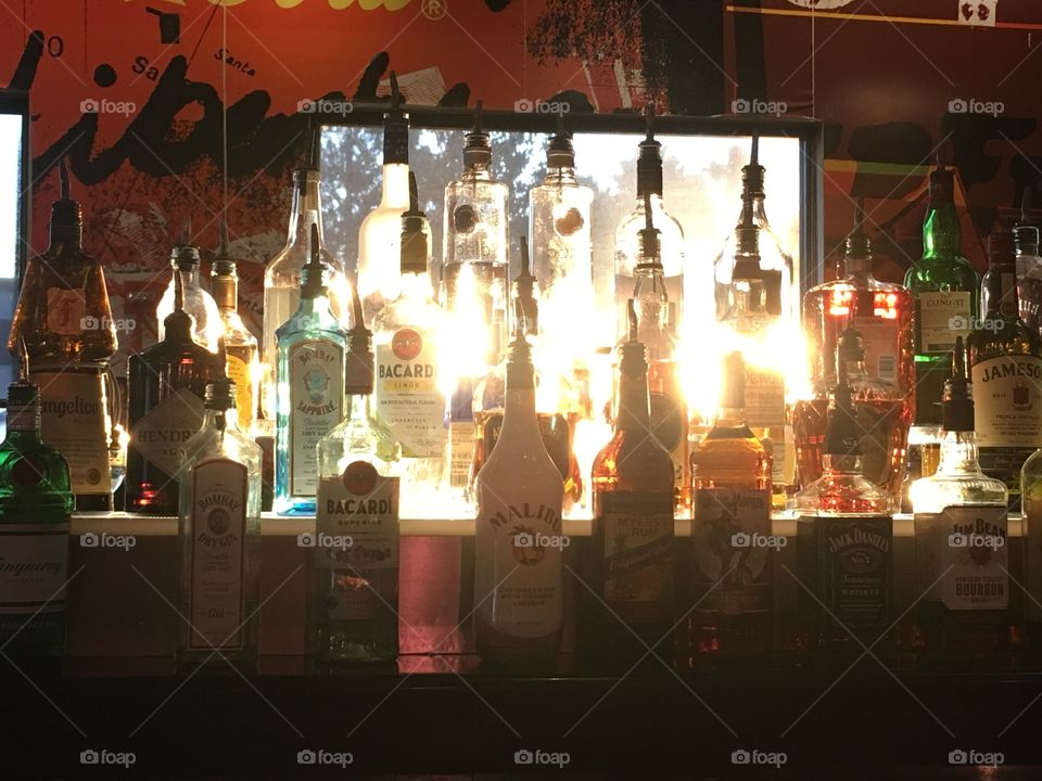 Sunshine shining through liquor bottles at the bar