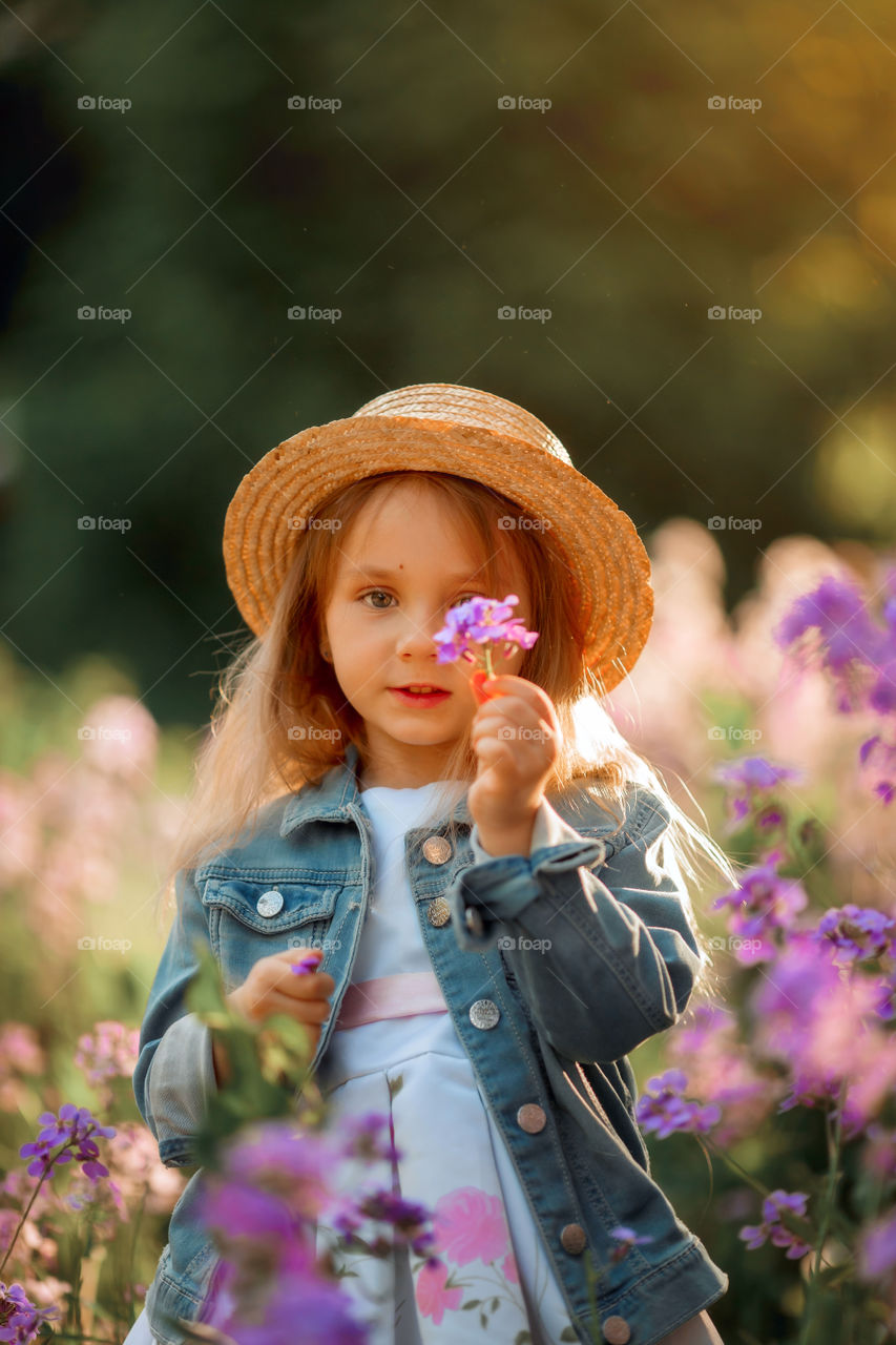 Cute little girl portrait in blossom meadow at sunset 