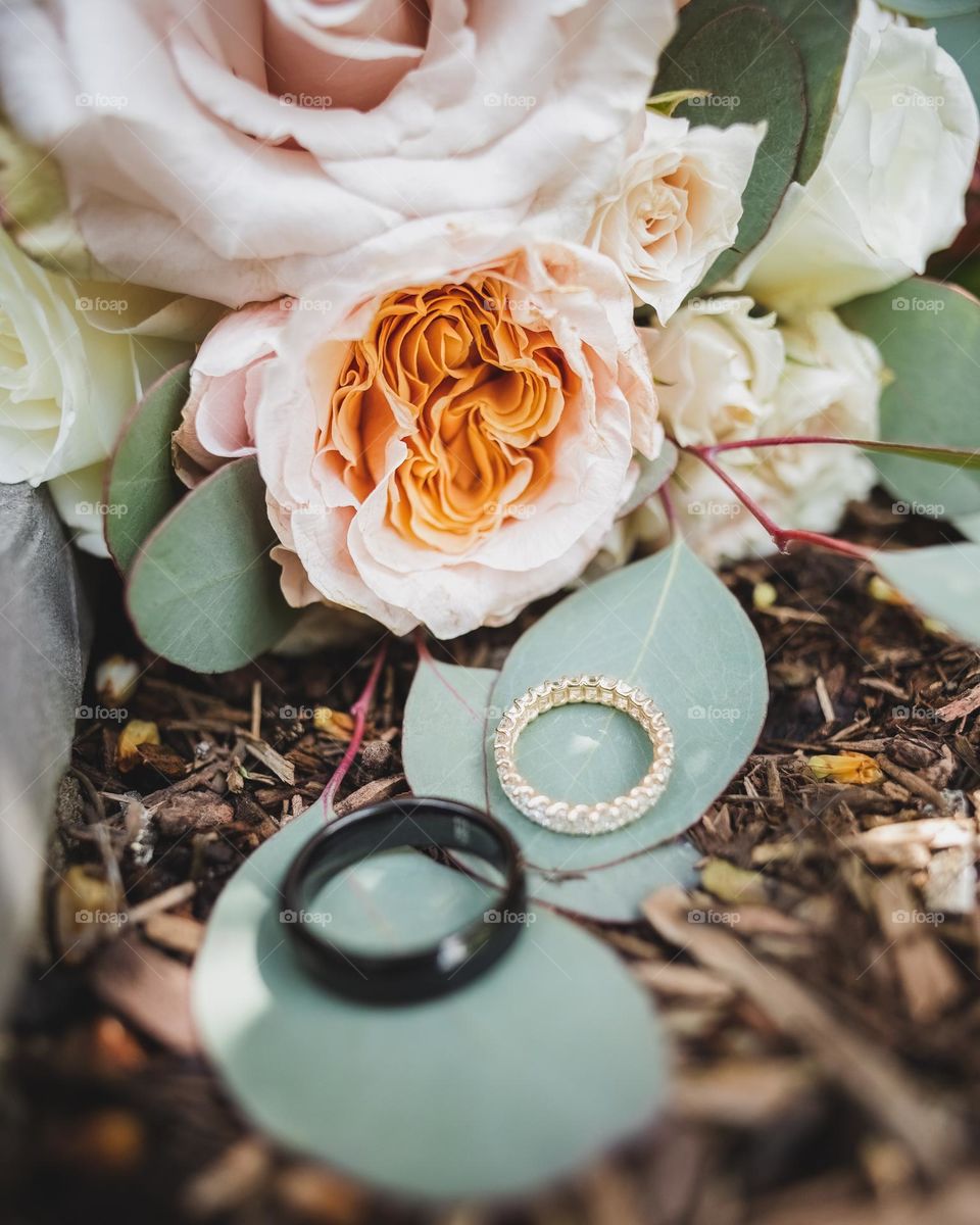 Close up macro shot of wedding rings and a bouquet of beautiful flowers 