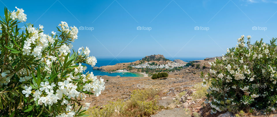 Panoramic distant view at the Lindos whitewashed village with ancient Acropolis and medieval castle build on clifftop rock. Lindos. Greece. Europe