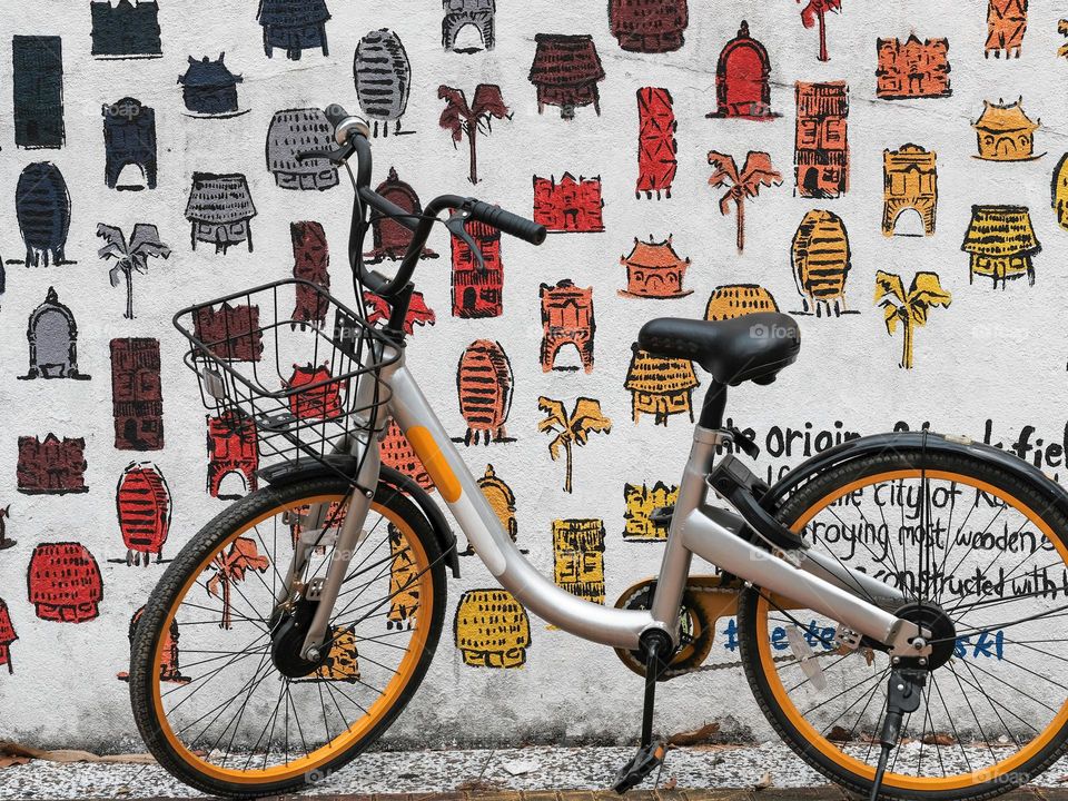 Bicycle for hire parked against an arty wall im Kuala Lumpur