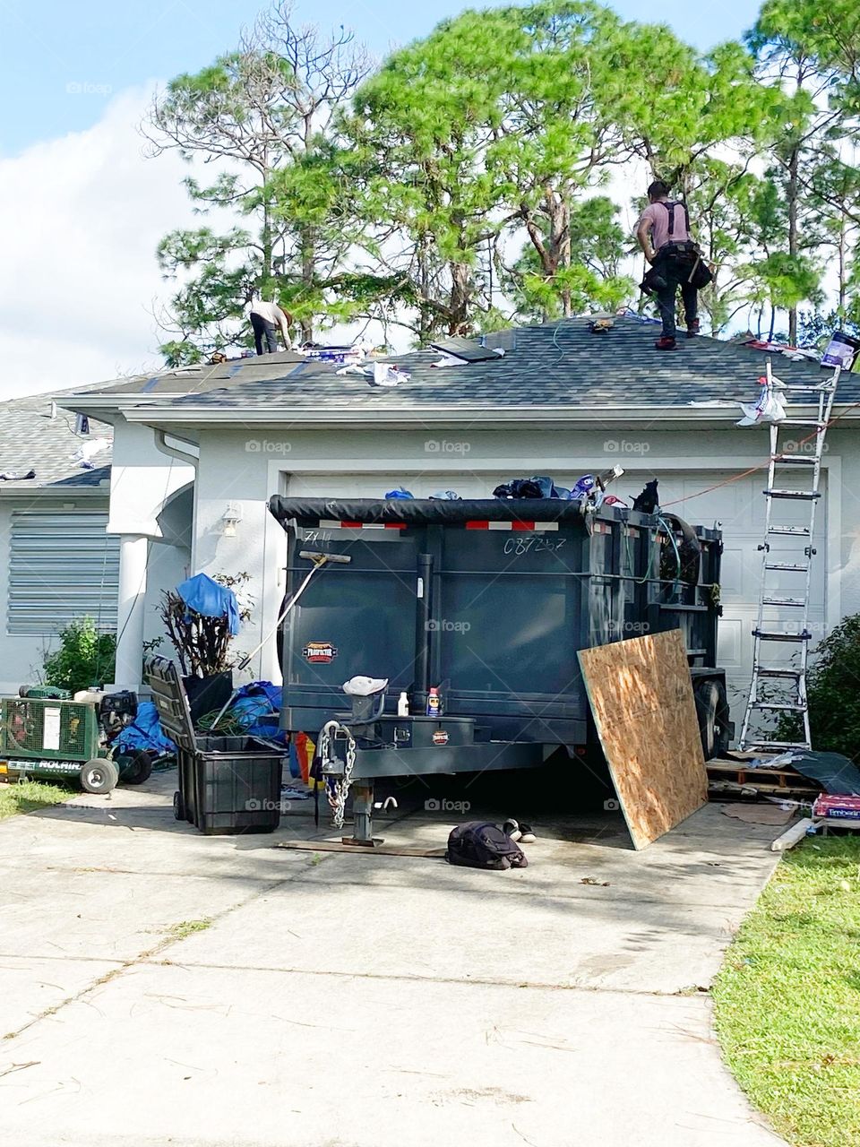 Roofers working with gear and tools in the driveway.