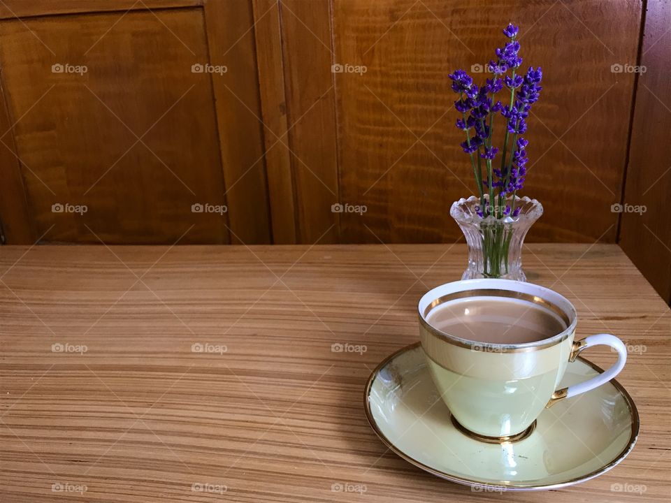 Cup of nes coffee with lavender flowers in a vase from the glass on a wooden table.