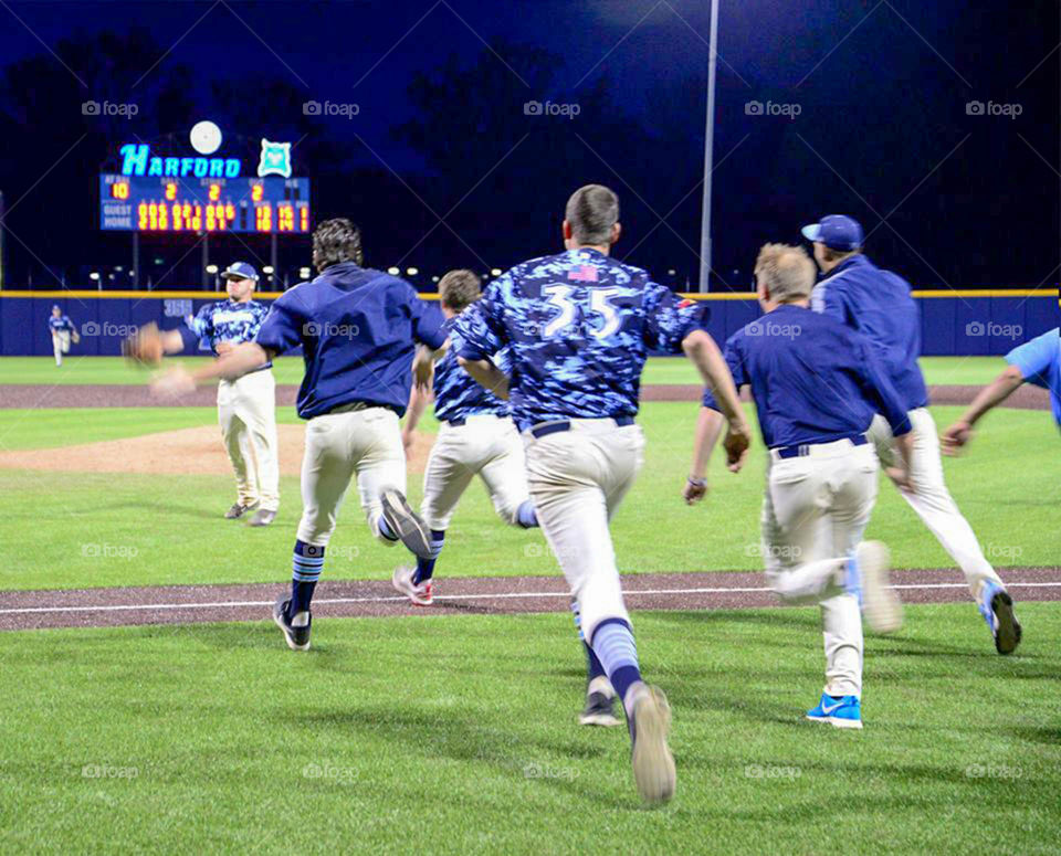 Racing toward the dogpile. College baseball players rejoice over divisional win and rush onto the field for traditional dogpile