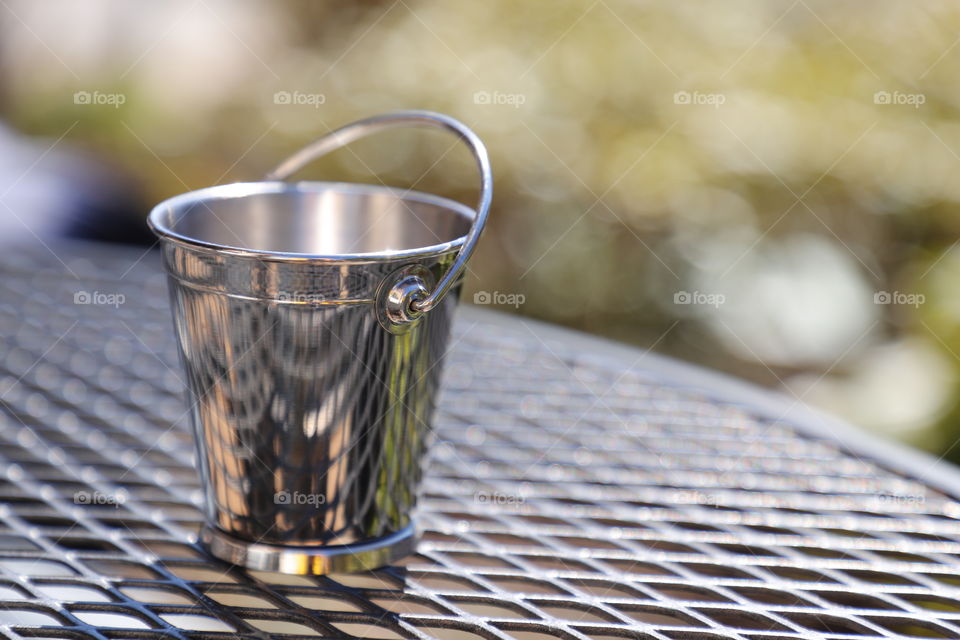 Lit metallic bucket on top of metallic table on a patio 