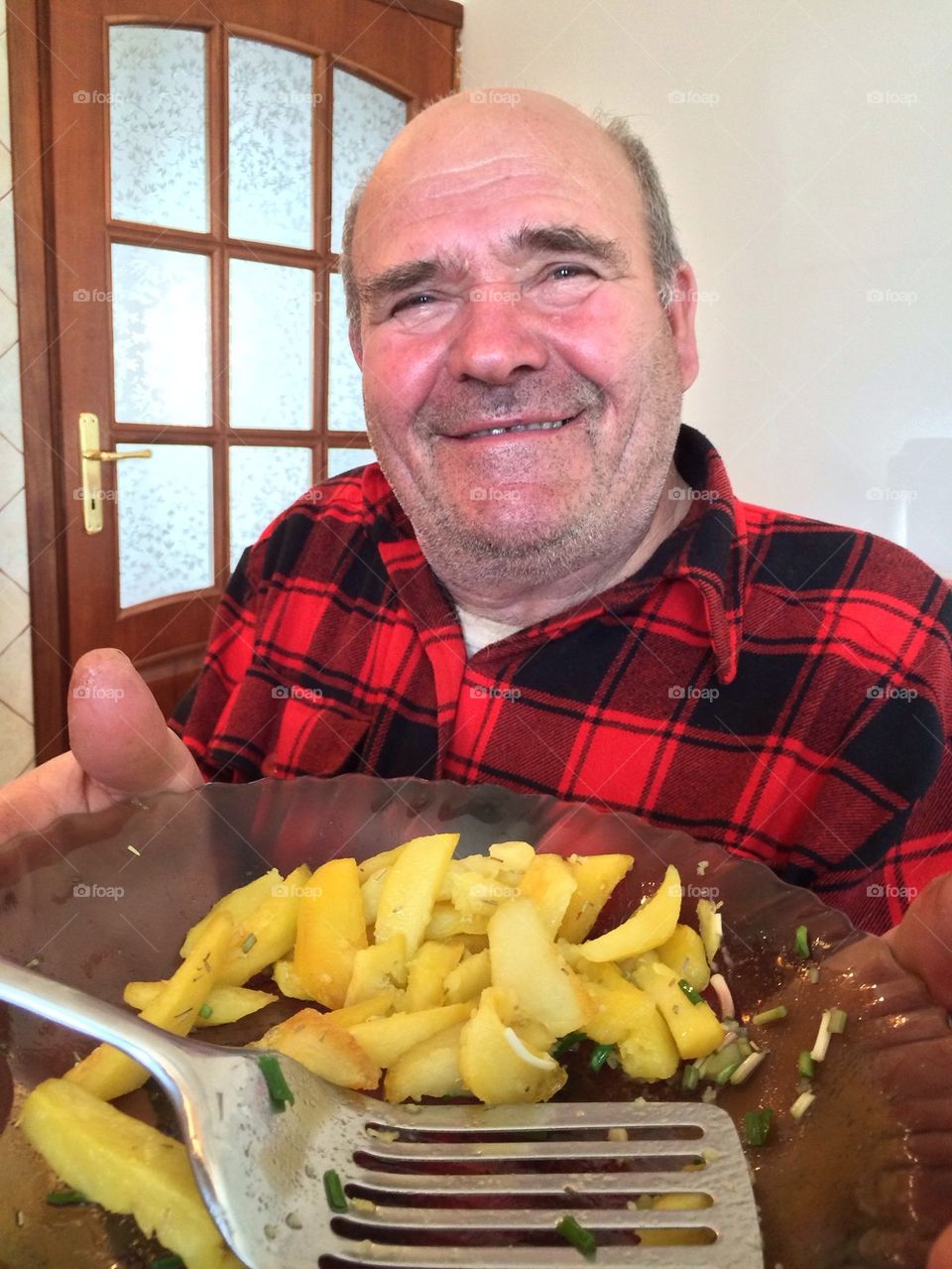 Happy old worker with a potatoes dish