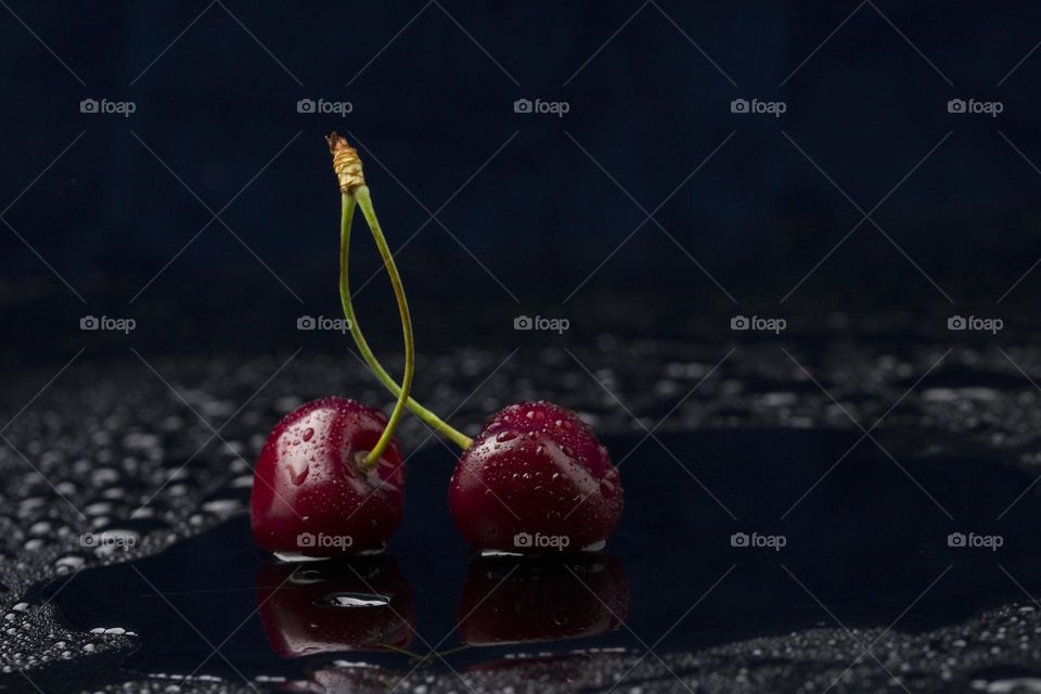 Close-up view of ripe organic cherries with water drops on blue background . Freshness concept.