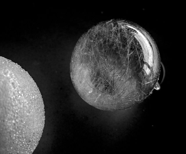 Two transparent and white glass balls on black background
