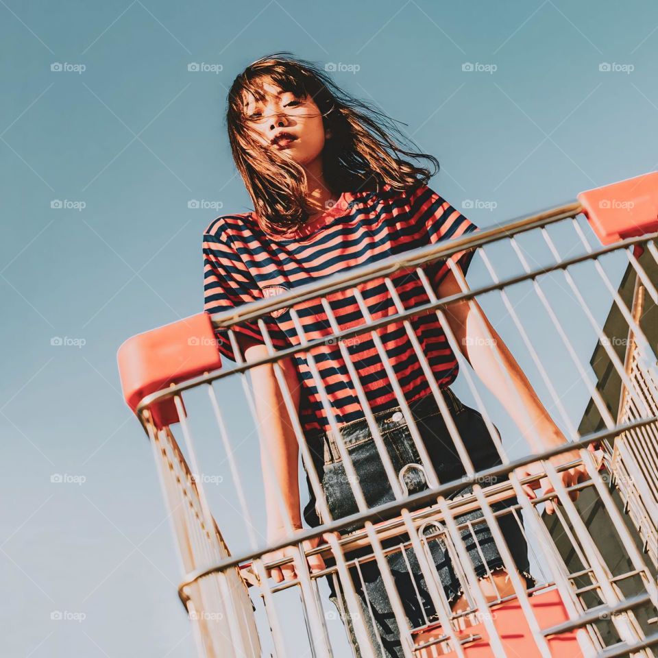 Low angle view of young woman standing against clear sky