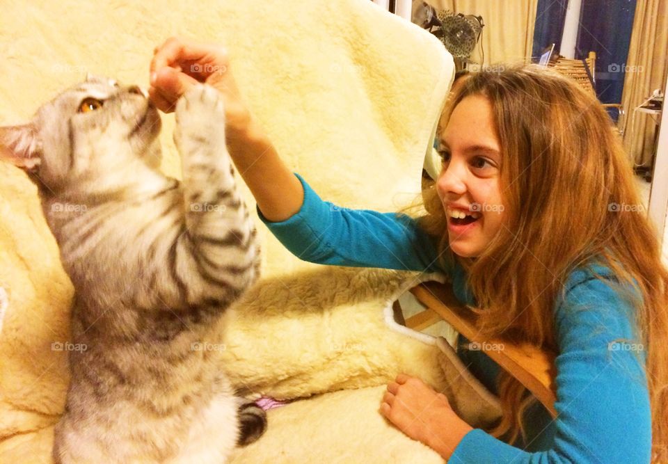 Daughter plays with cat giving it a cheese vitamin