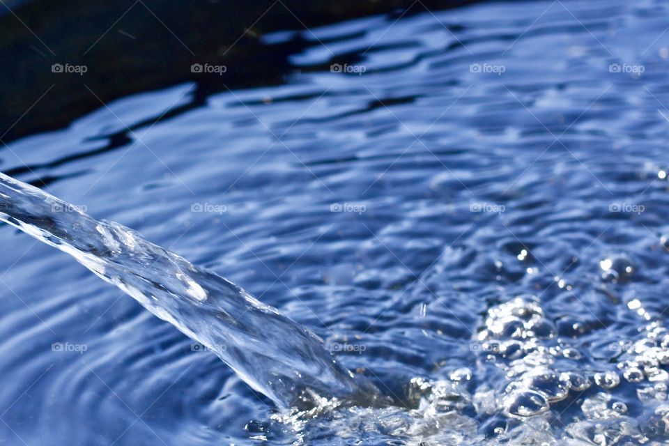 Isolated view of a gentle flow of splashing water, creating ripples and reflecting a deep blue sky