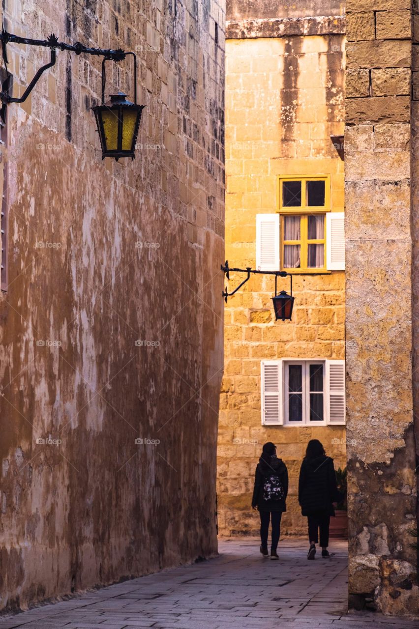 Two girls walking through the ancient streets of Mdina, Malta.