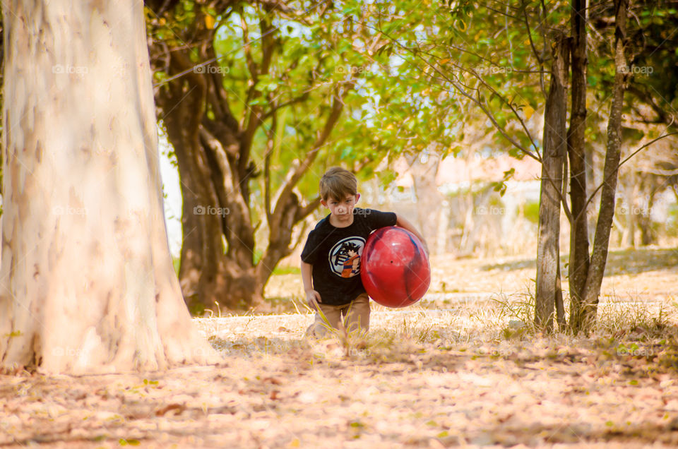 child playing with red ball in nature