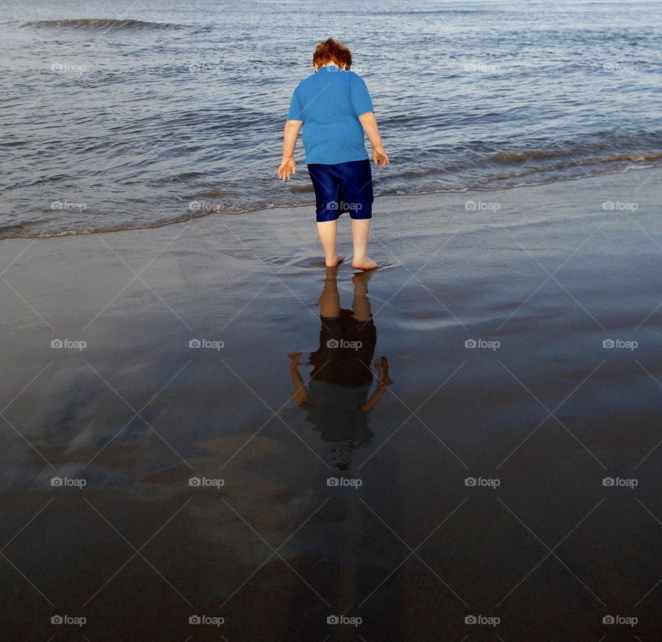 Red headed boy walking on shore. 