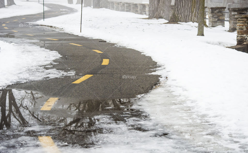 Bicycle path road covered in snow and ice and melting snow on foggy day in winter conceptual healthy lifestyle and winter adventure background