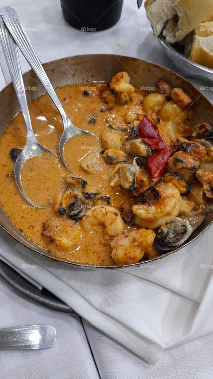 cazuela de mariscos en salsa con dos cucharas