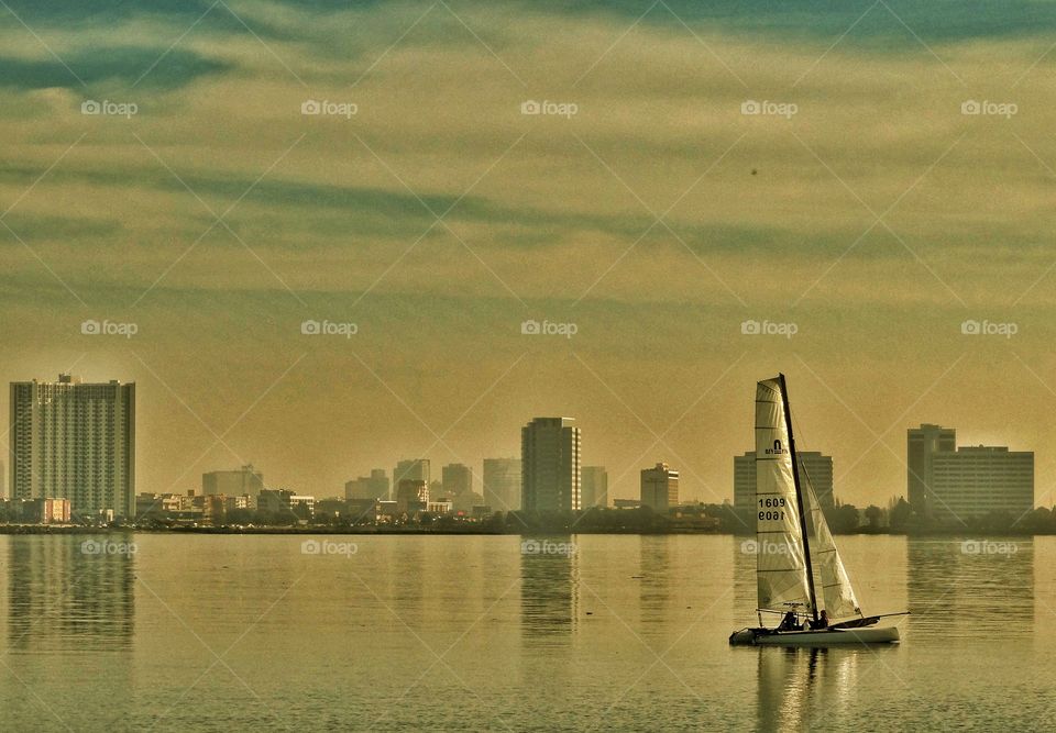 Sailing In The Golden Hour. Sailboat In City Harbor Before Sundown
