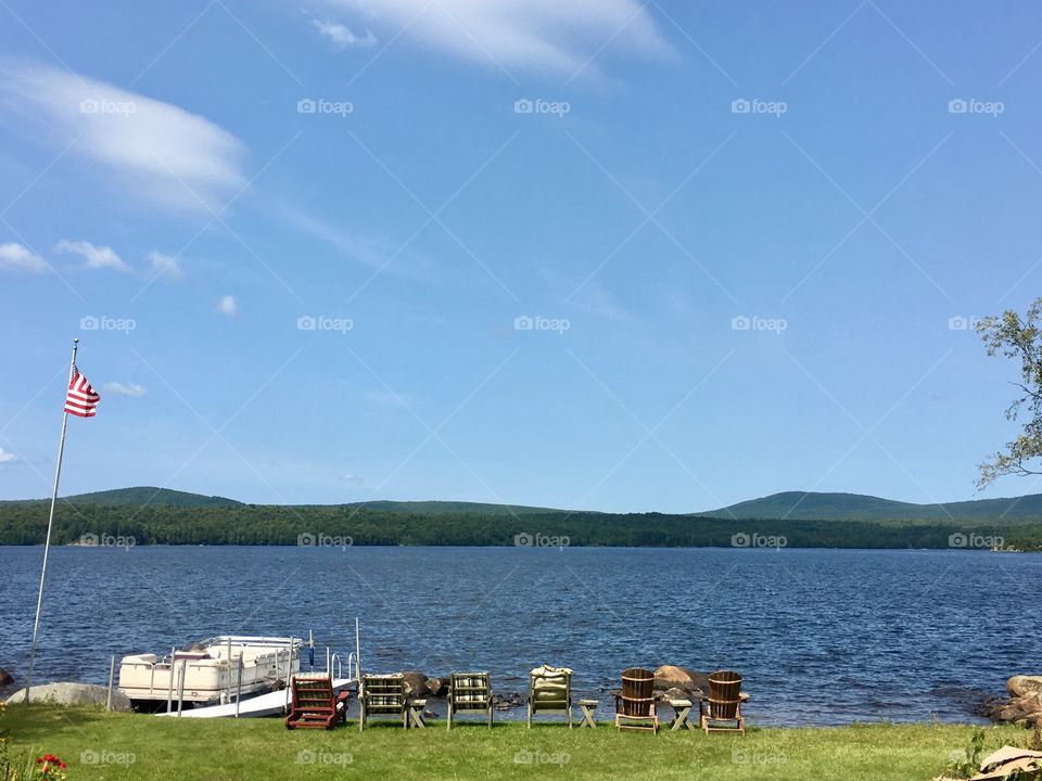 Adirondack Mountains at Chateaugay Lake New York, lakeside boat and chairs 