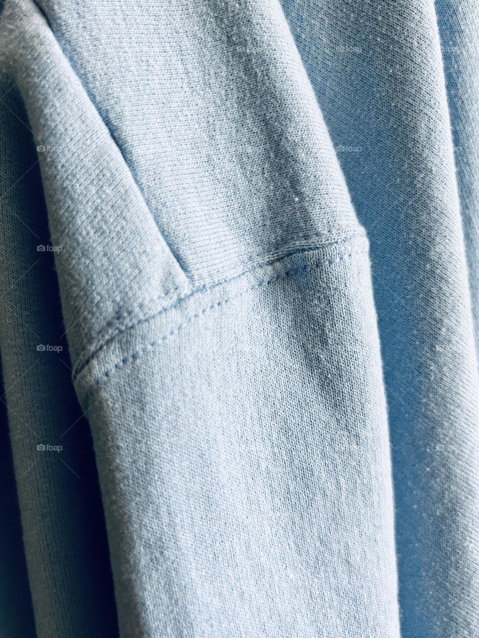 Full frame closeup of baby blue pastel sweatshirt draped into folds